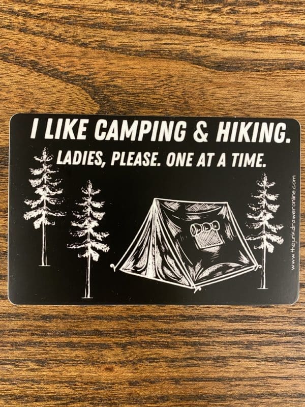 Sticker with trees and a tent and the text I like camping & Hiking. Ladies, please. One at a time.